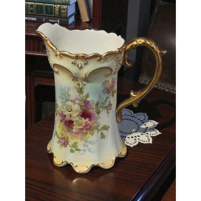 The Antique Royal Devon S.& F. Co. England Hand Painted Floral Gilded Pitcher is a vintage porcelain pitcher with a...