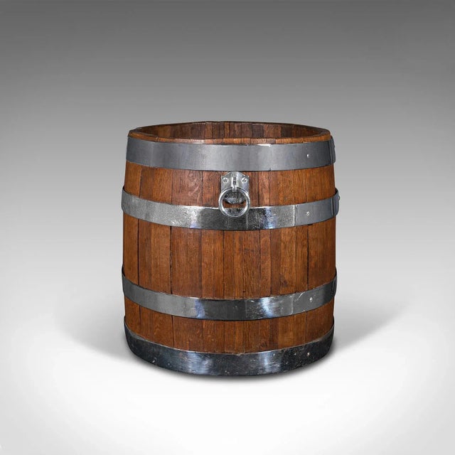 This is an antique fireside bin. An English, oak and chrome coopered half barrel log or coal cask, dating to the Victorian...