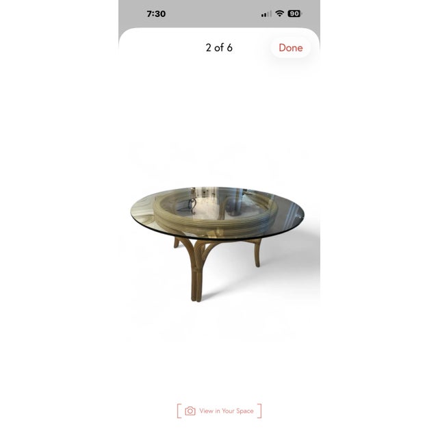 A beautifully sculptural vintage 1970s pencil reed rattan dining table featuring a substantial 54-inch round glass top and...