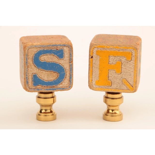 Pair of lamp finials crafted from vintage alphabet blocks topping solid brass finial bases sized to fit a standard lamp...