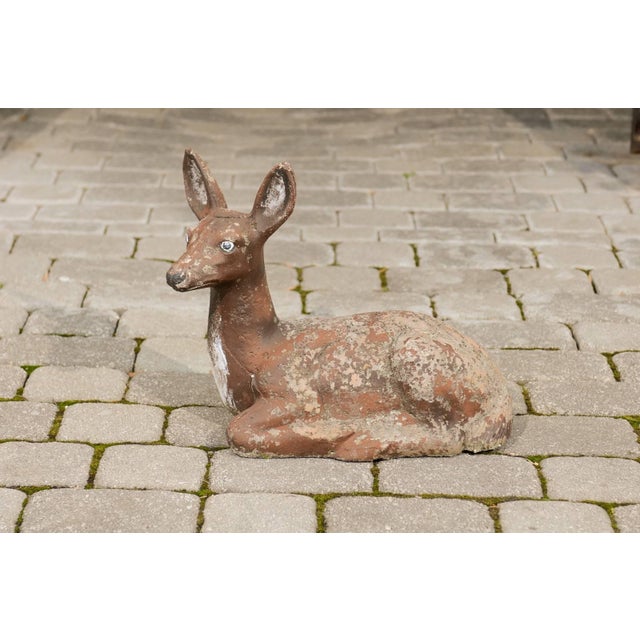 A vintage French painted seated deer sculpture cast in reconstituted stone from the mid 20th century. This French painted...