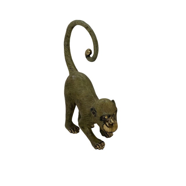 A charming cast bronze monkey sculpture, capturing a moment of curiosity and movement with a playful yet refined...