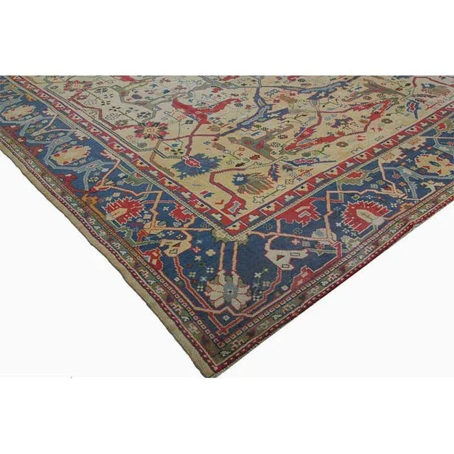 This traditional handwoven antique Turkish Oushak style rug features an elegant yellow-colored field with an allover...
