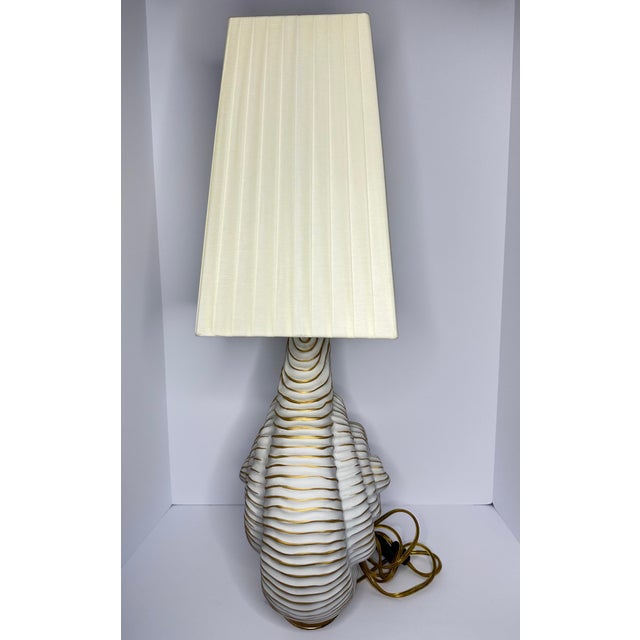 A beautifully crafted Italian porcelain table lamp by Mangani, featuring a striking sculptural nautilus shell silhouette...