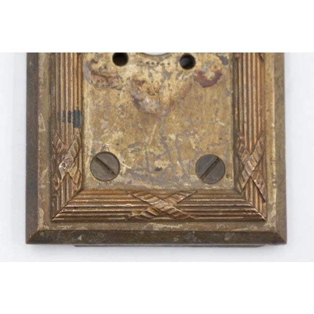 Reclaimed brass electrical wall plate cover with a circular cut out with four small holes on each corner. The original use...