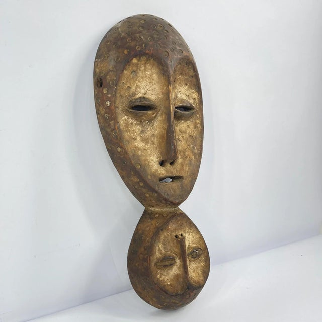 Lega masks, wooden and featuring elongated faces with a central ridge, almond-shaped eyes, and symbolic geometric...