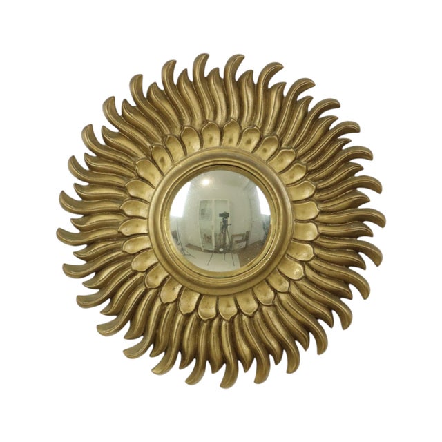 A beautiful and rare vintage sunburst mirror featuring convex glass and undulating rays; crafted from gold-colored resin,...