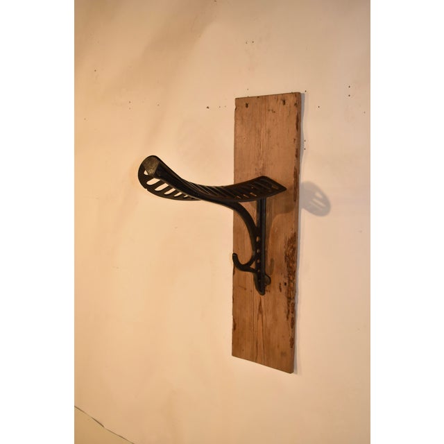 19th century cast iron saddle stand made and stamped by J W Fiske and Co, NY. The saddle stand is mounted on an old pine...