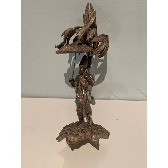 A unique piece - a man, perhaps a jester, holding an umbrella with a bird. The piece would make a nice decorative item or...