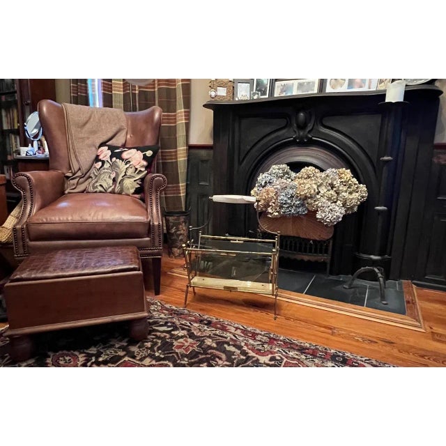 A striking and sophisticated mid-century French magazine rack executed in solid brass, smoked glass, and exceptionally...