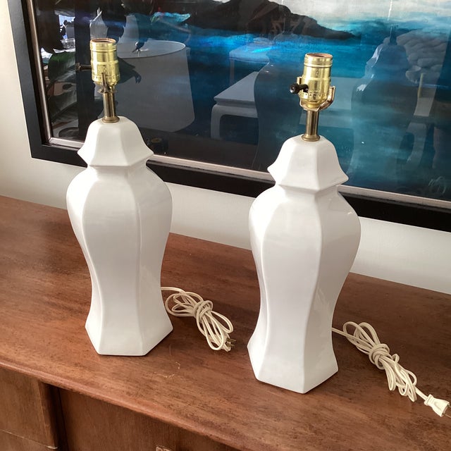 A sophisticated pair of sculptural white ceramic table lamps featuring a faceted, pagoda-inspired silhouette. The crisp...
