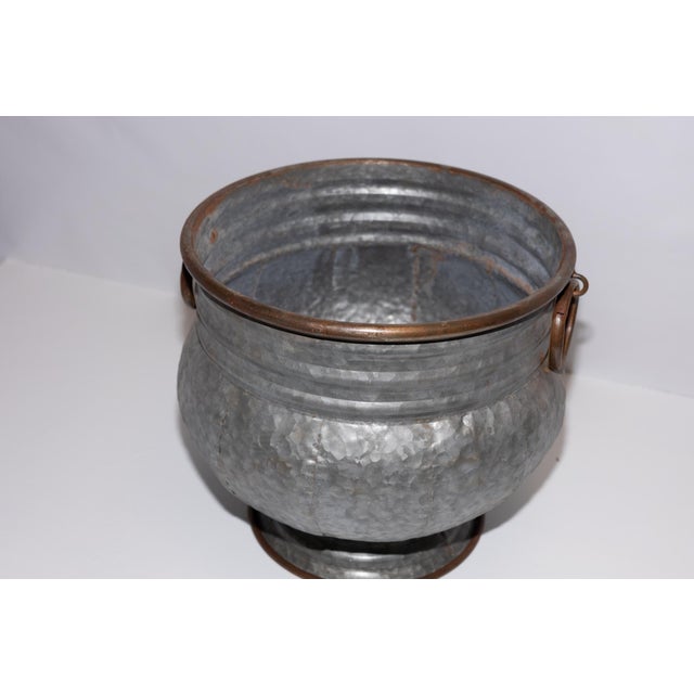This galvanized metal pot features a graceful bulbous shape with copper-colored rims and decorative rings. Great accent...