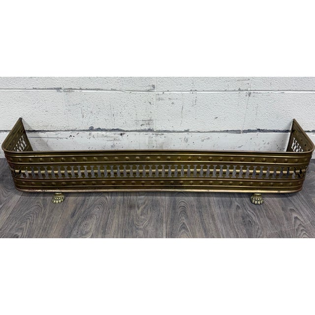 This is a beautiful antique English brass fireplace fender with pierced gallery sides, riveted detailing, and decorative...