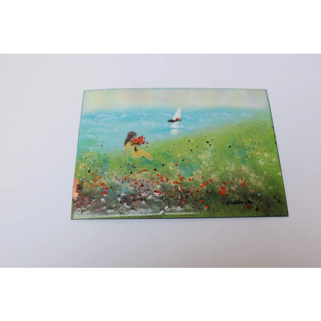 Enamel on copper plaque depicting a girl in a waterfront field with flowers with a sailboat in the distance (ca 1950s,...