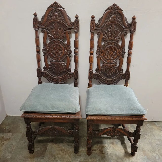 A pair of heavily carved English Jacobean style oak hall chairs. They high backs measuring almost 51" high and hand carved...