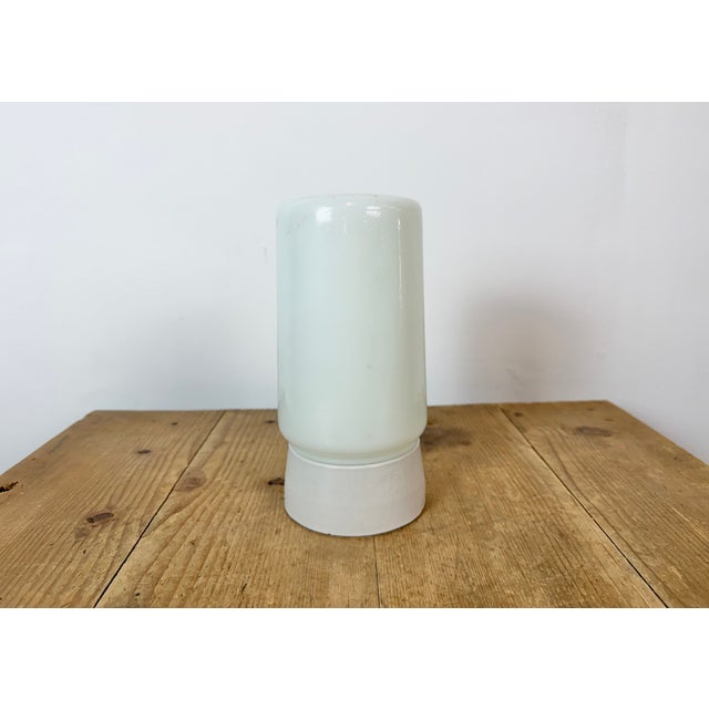 Vintage industrial light made in Poland during the 1970s. It features a white porcelain ceiling mounting and a milk glass...