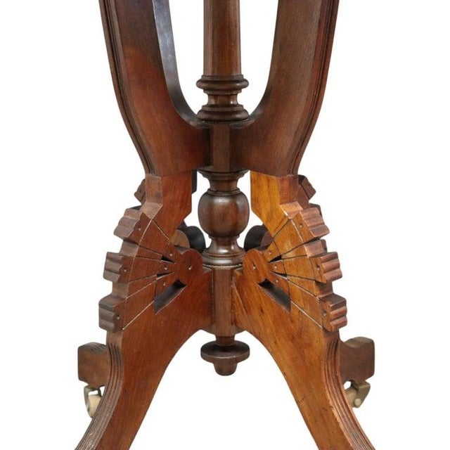 An antique Eastlake style carved walnut square table, dating from approximately 1890. This elegant table features a...