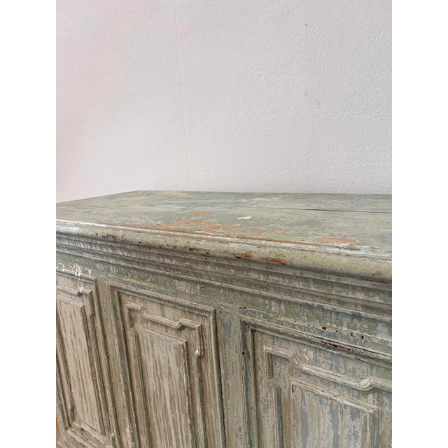 A substantial antique French buffet in solid pine, dressed in a soft sage-green paint that has worn through decades of use...