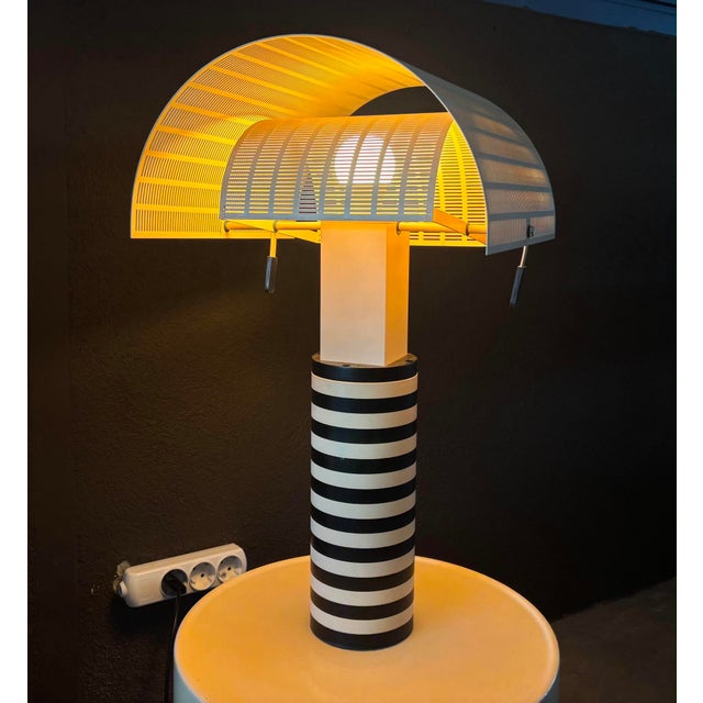 Shogun table lamp by mario botta for artemide, 1986 ca. Embossed cast iron, enamelled metal, enamelled metal grid....