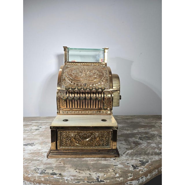 Decorative “National” cash register from around 1900, beautifully crafted in engraved and gilt brass. This impressive...