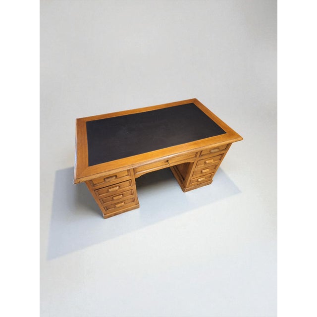 Executive desk made of oak with a black leather-covered top. The style and era are classic 1930s/40s. It features two rows...