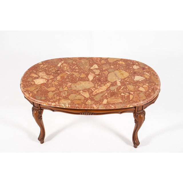 Elegant vintage coffee table in the Louis XV style, featuring a richly figured oval stone top resting on a beautifully...