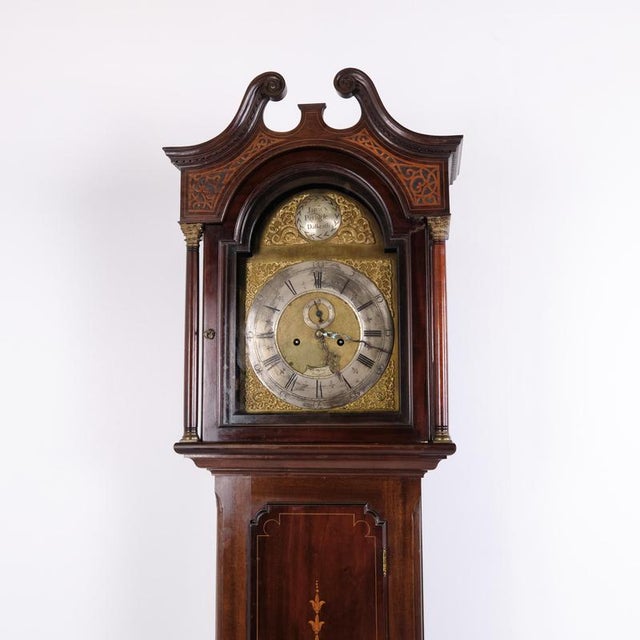 English longcase clock crafted in mahogany with marquetry decoration and a brass dial. The clock dates from around the...