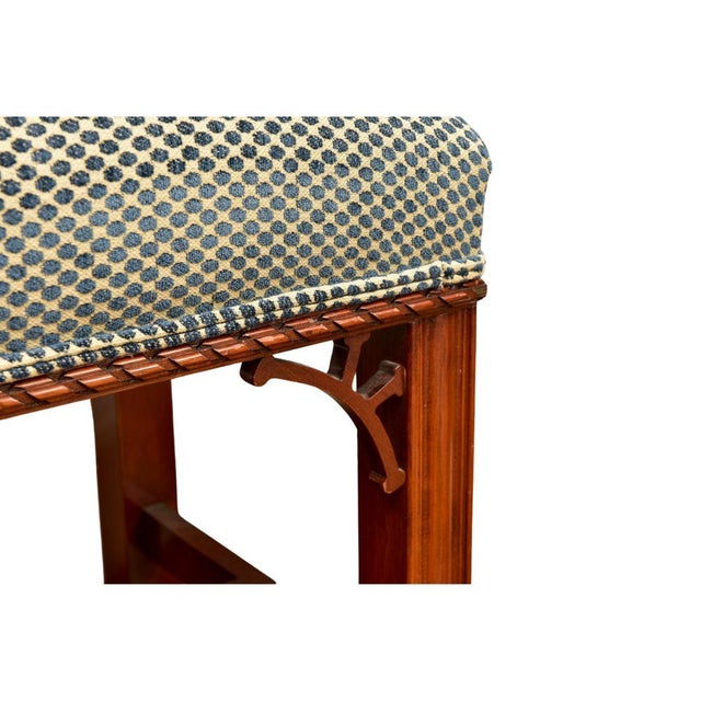 A carved wood bench with details at apron, straight legs with single stretcher and upholstered in a blue dot flocked velvet.