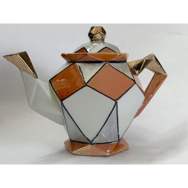 This teapot exemplifies the Art Deco movement of the 1920s - 1930s, characterized by bold geometric patterns, vibrant...