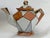 This teapot exemplifies the Art Deco movement of the 1920s - 1930s, characterized by bold geometric patterns, vibrant...