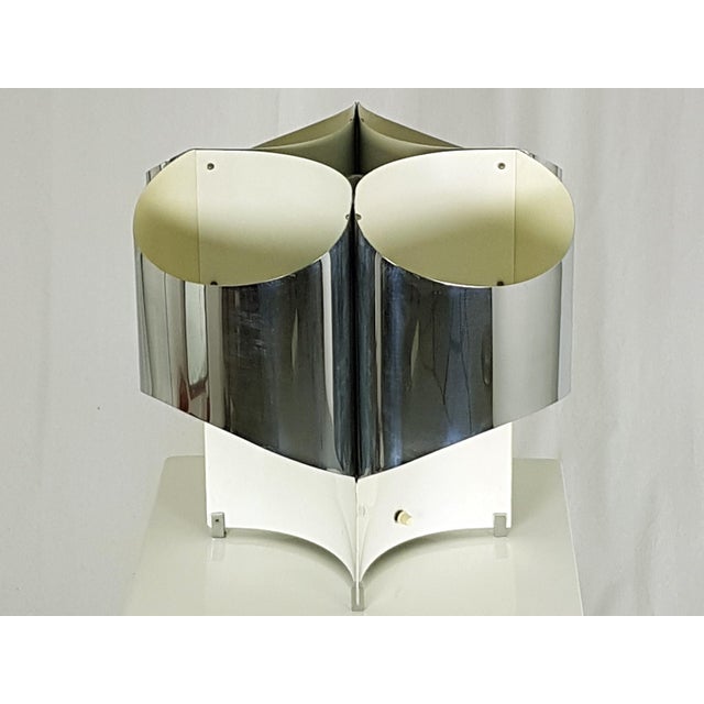 This large 4-lights lamp was designed in Italy in the 1960s. It is made of bent chromed metal and bent painted metal; the...
