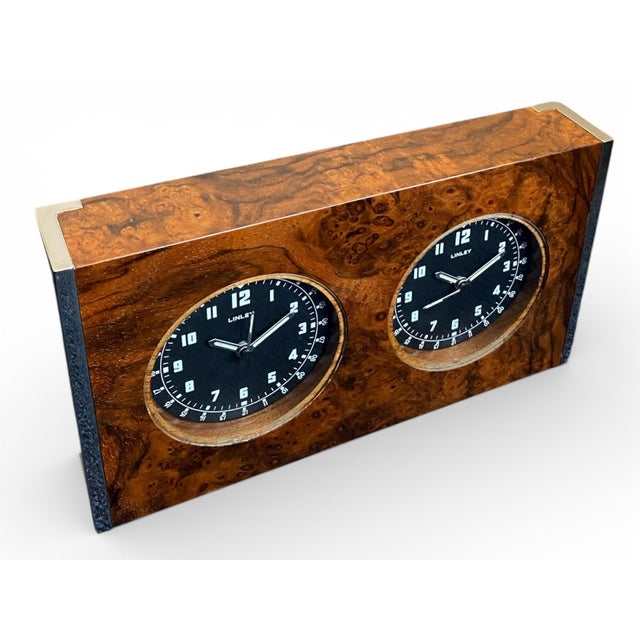 A refined executive desk clock by linley, crafted in richly figured walnut burl veneer with polished chrome end mounts and...