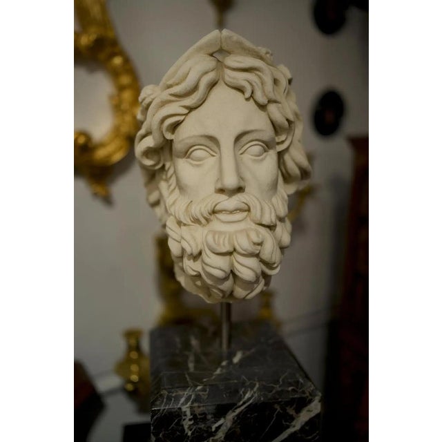 A beautiful 20th century hand carved marble Greek head bust with a black marble base. Stunning detail and skill from the...