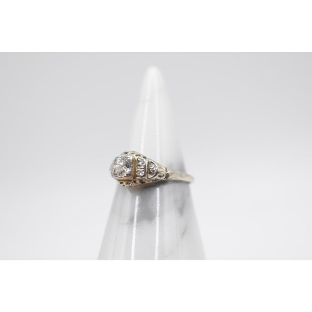 This is a gorgeous Art Deco diamond ring set in 14kt white gold filigree. The center stone is a transition cut diamond of...