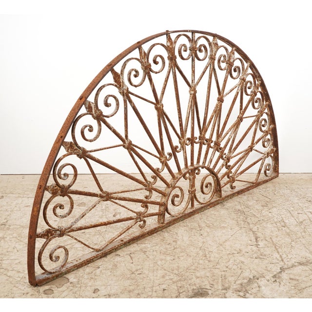 Reclaimed French style arch shaped transom made of wrought iron with a rust exterior. It features a semi circular design...