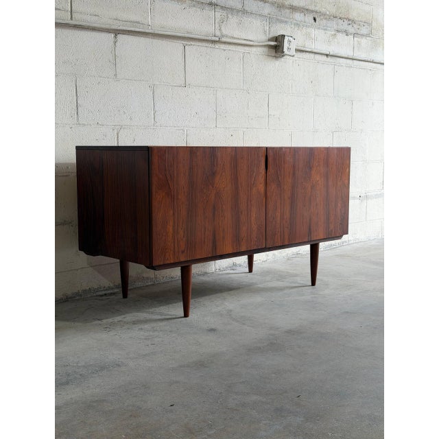 This minimalist low-profile sideboard credenza features a streamlined rectangular cabinet frame supported by elegant...