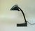 A banker's lamp crafted in a minimalist art deco style with a stepped base, manufactured by dr. Ing. Schneider & co.,...
