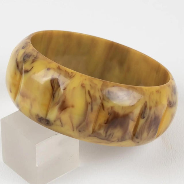This is a stunning banana and chocolate marble Bakelite carved bracelet bangle. It features a chunky, domed shape with...