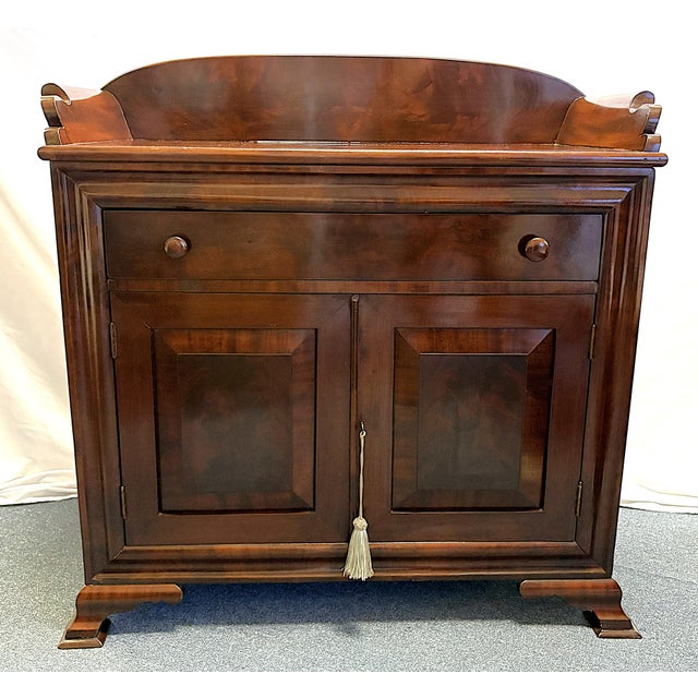 Timeless dry sink cabinet from the mid 20th century. It is made of mahogany with a lower double door cabinet with a...