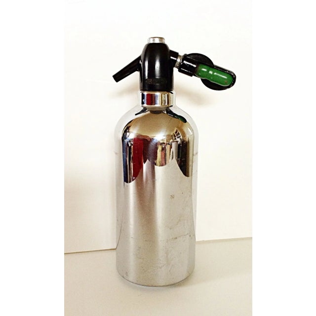 A steel encased glass seltzer water container that measures 4.5" in diameter. Thumb tabs make it easy to replace the gas...