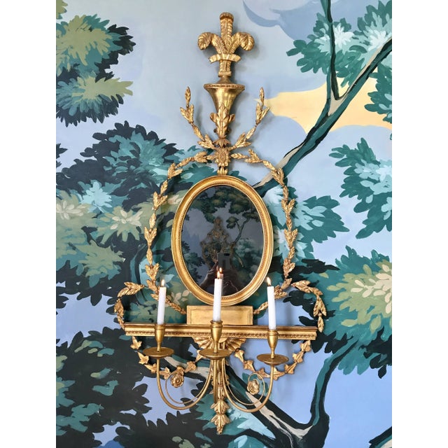 This extremely rare pair of giltwood girandole mirrored wall sconces is English and was produced in the early 19th century...