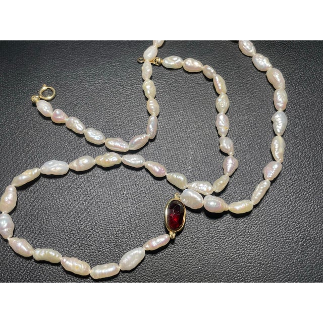 This elegant 14k gold jewelry set features a matching necklace and bracelet composed of iridescent, rice-shaped freshwater...