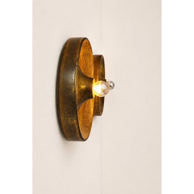 Pair of disc-shaped wall sconces in patinated brass, made in Italy in the 1970s. Timeless design for this classic in this...