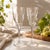 Elegant pair of vintage clear glass champagne glasses featuring a delicate etched grape and vine motif. The tall, gently...