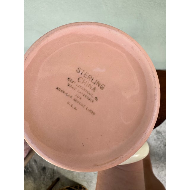 A sleek and historically significant blush pink ceramic coffee pot with a clean white lid and white interior, made...