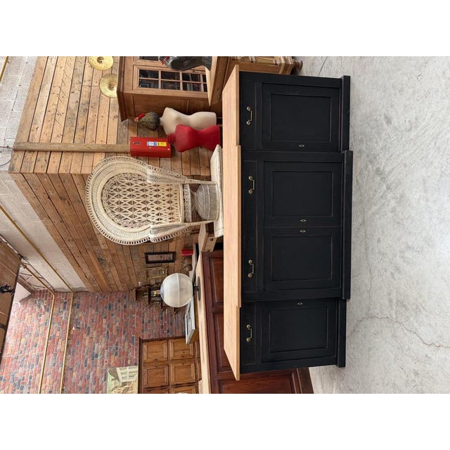 This antique sideboard has been fully restored. It features a black patinated base with a raw wood top. It is fitted with...