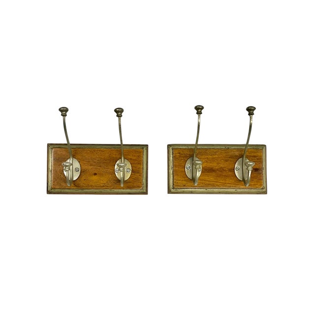 Charming pair of vintage wall-mounted double hooks featuring warm, aged wood plaques with silver tone metal hooks and...