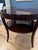 This polished wood side table has a dark mahogany finish and a round silhouette. This piece has a single integrated drawer...