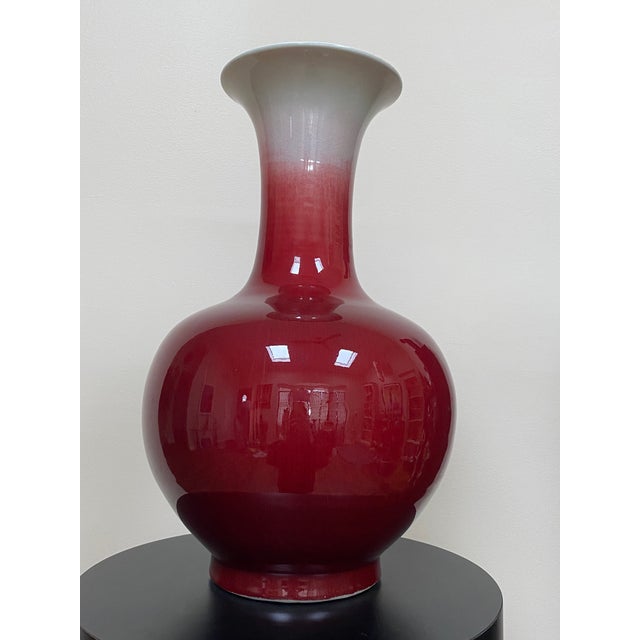Mid-20th-century Chinese porcelain bottle vase finished in a tonal sang de boeuf, or oxblood, glaze. Its substantial scale...
