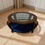 Add a statement centerpiece to your living room with this elegant round glass-top coffee table featuring a sculptural...